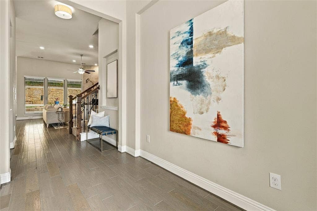 Foyer entry with wood-finish flooring, recessed ceiling lighting, and a dark-toned wood staircase with iron balusters