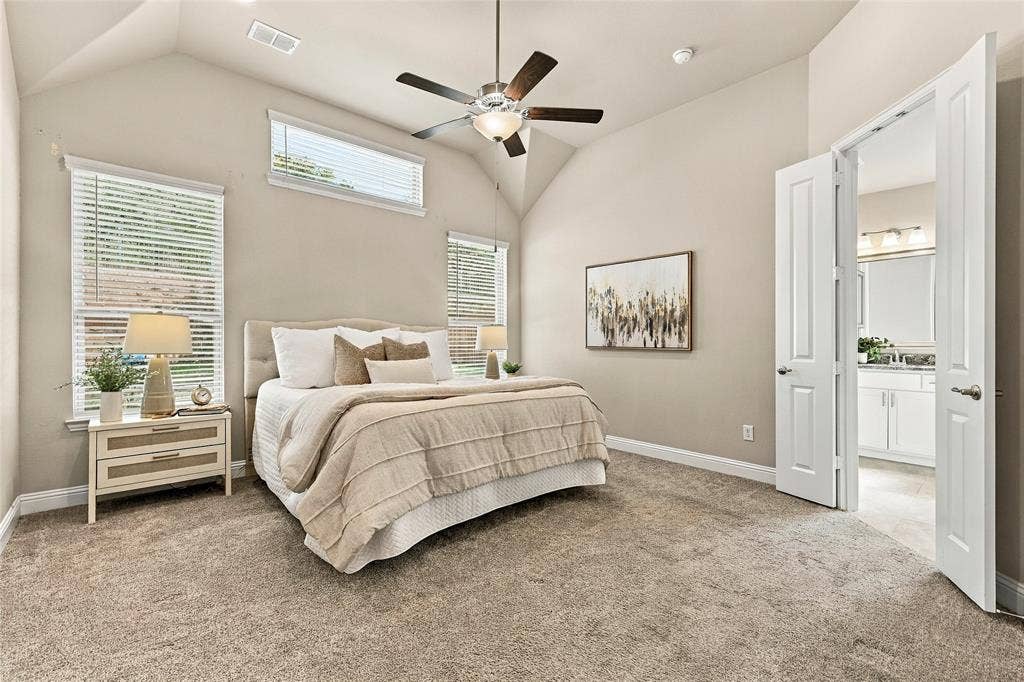 Vaulted ceiling, neutral wall tones, multi-pane window configuration, and overhead ceiling fan