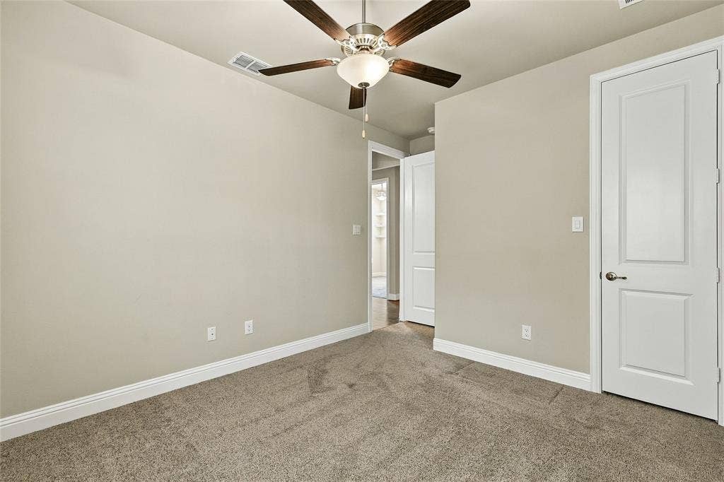 Neutral wall palette, wall-to-wall carpeting, ceiling fan with integrated lighting, and two-panel interior doors