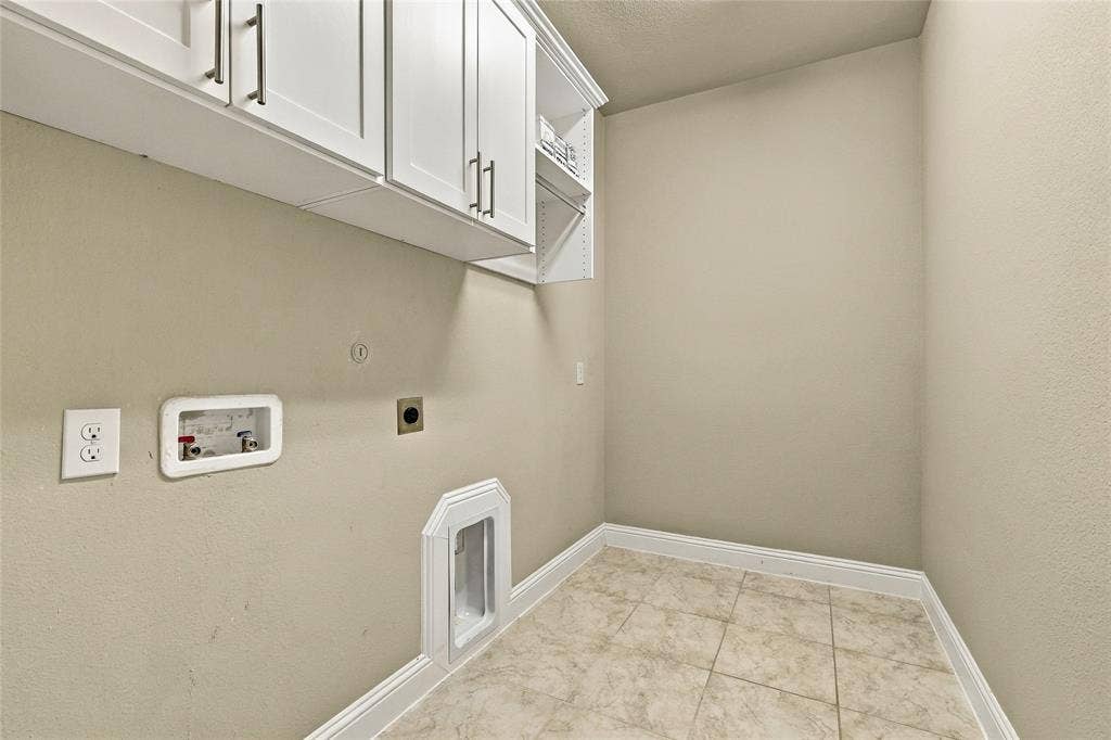 Utility area featuring white shaker-style cabinetry with modern bar hardware, an integrated laundry box, ceramic tile flooring, and a dedicated wall-mounted dryer vent