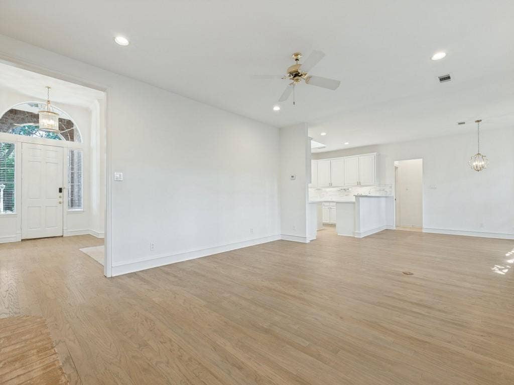 2817 Mayfair Lane, McKinney, TX 75071 Open-concept interior featuring light wood-finish flooring, recessed lighting, a ceiling fan, white cabinetry, and a high-arched entryway