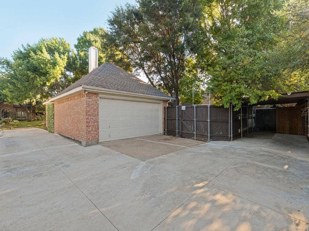 2817 Mayfair Lane, McKinney, TX 75071 Detached brick garage featuring a multi-pitched shingled roof, chimney, concrete driveway, and attached metal-framed carport