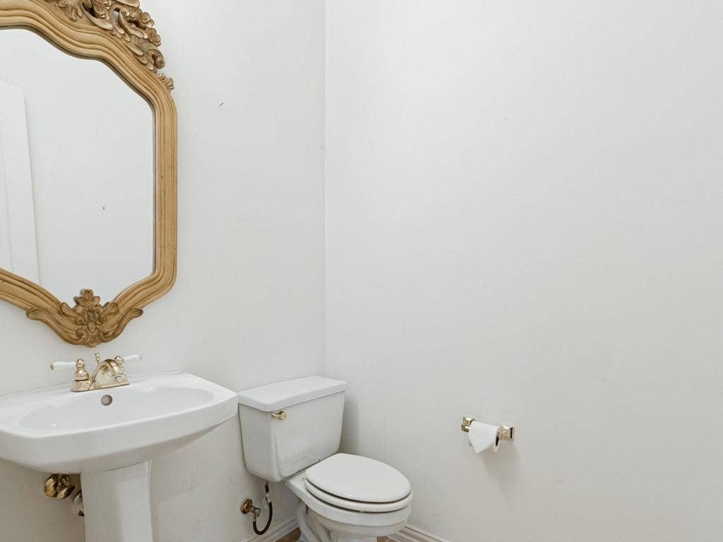 2817 Mayfair Lane, McKinney, TX 75071 Pedestal sink featuring a polished metal widespread faucet and a decorative wall-mounted mirror with an ornate gold-finish frame
