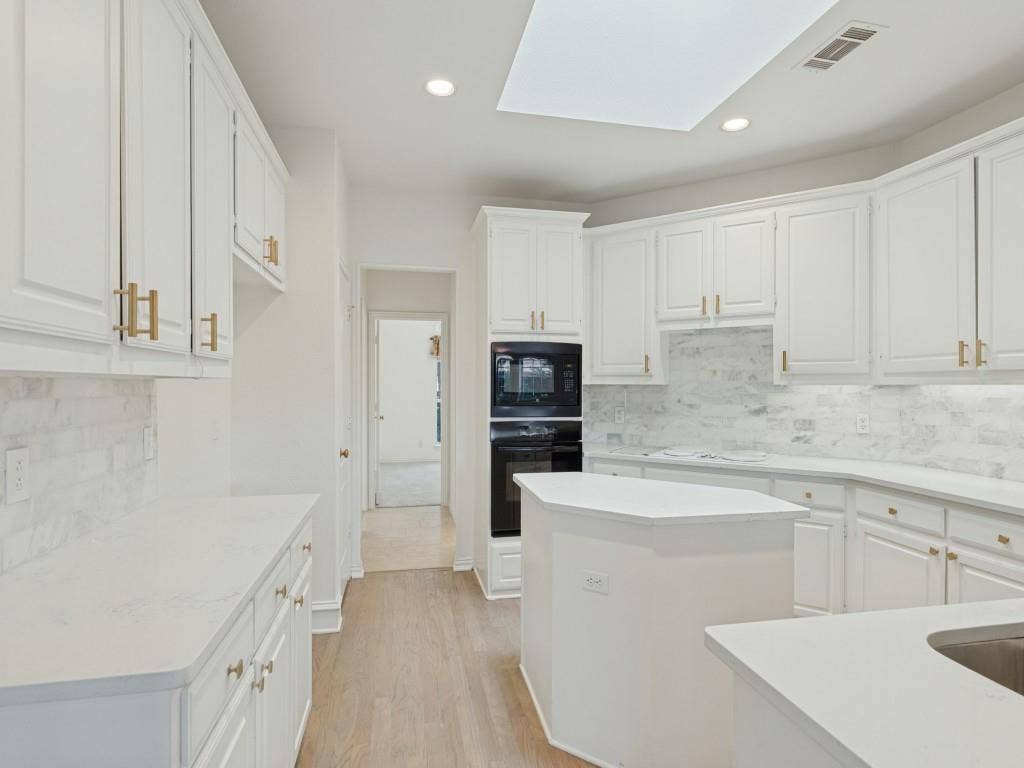 2817 Mayfair Lane, McKinney, TX 75071 Kitchen featuring white shaker-style cabinetry with gold-tone hardware, stone-finish backsplash, quartz countertops, integrated double oven, and recessed ceiling lighting