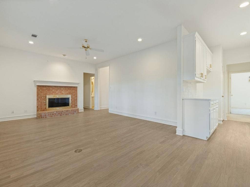 2817 Mayfair Lane, McKinney, TX 75071 Living area featuring wood-finish flooring, recessed lighting, a brick fireplace with a mantle, and built-in white cabinetry
