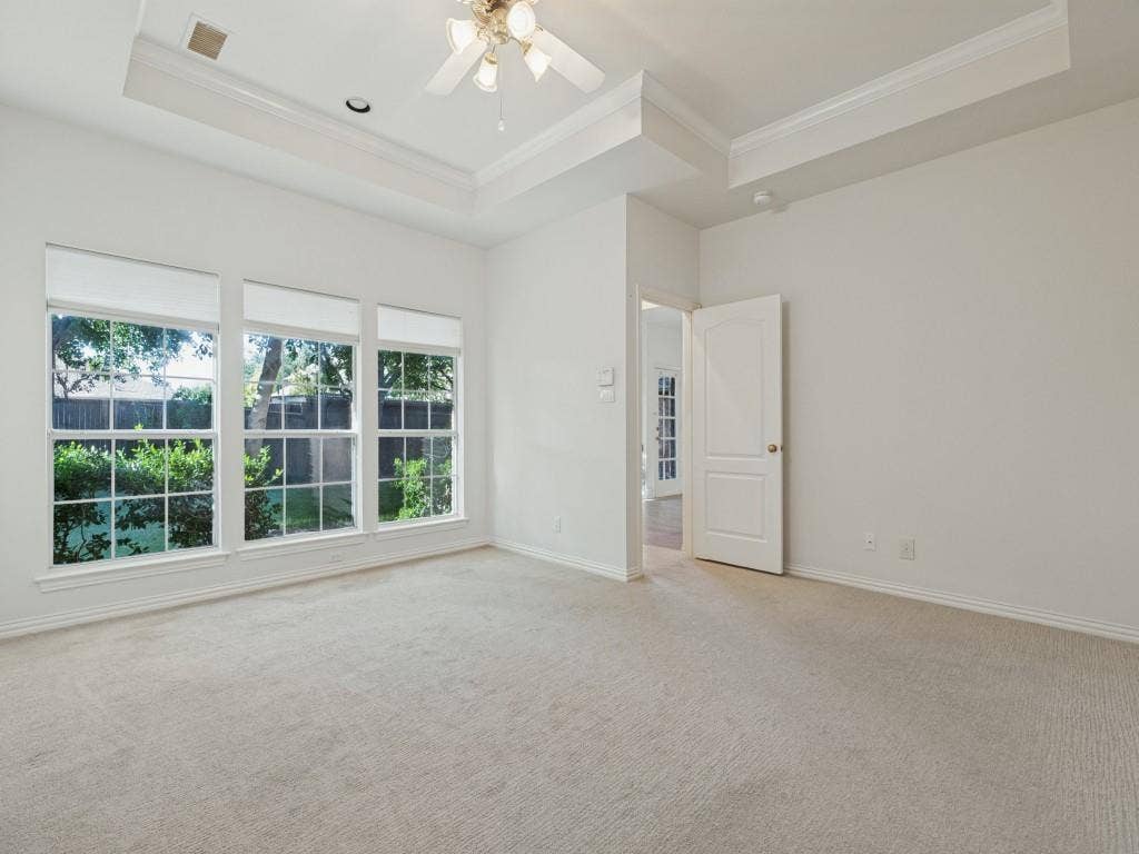 2817 Mayfair Lane, McKinney, TX 75071 Tray ceiling with crown molding, three large windows with grid detailing, neutral carpeting, and a ceiling fan with integrated lighting