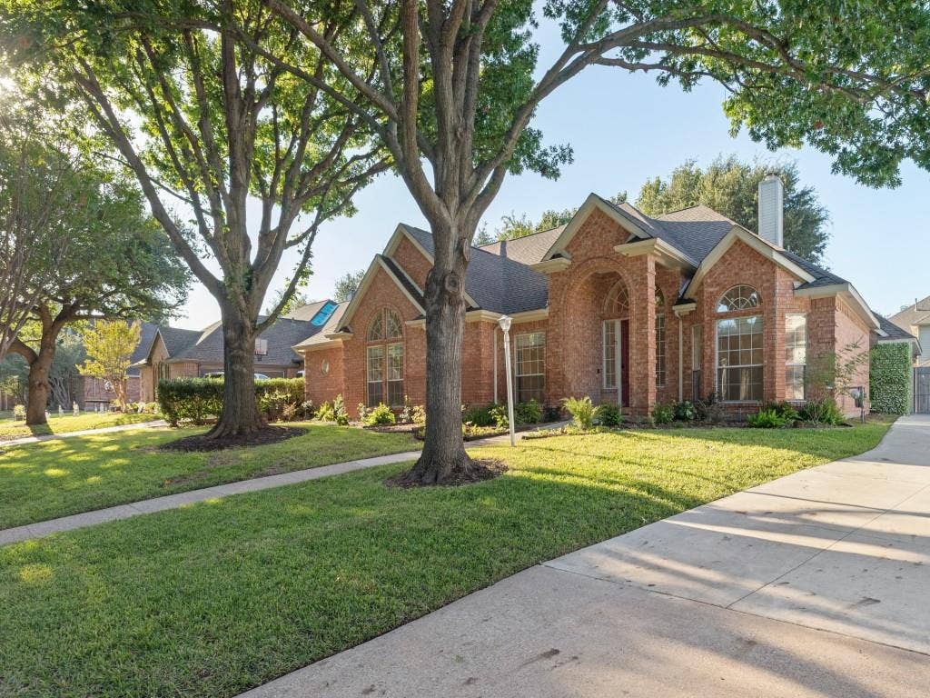2817 Mayfair Lane, McKinney, TX 75071 Brick exterior featuring a gabled roofline, arched entryway, multi-pane windows, and a concrete driveway