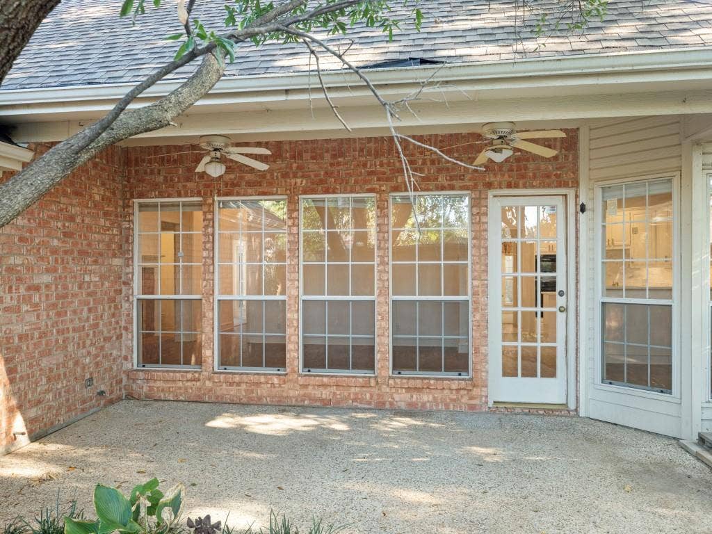 2817 Mayfair Lane, McKinney, TX 75071 Covered brick patio featuring a concrete floor, dual ceiling fans, grid-pane windows, and a glass-paneled exterior door