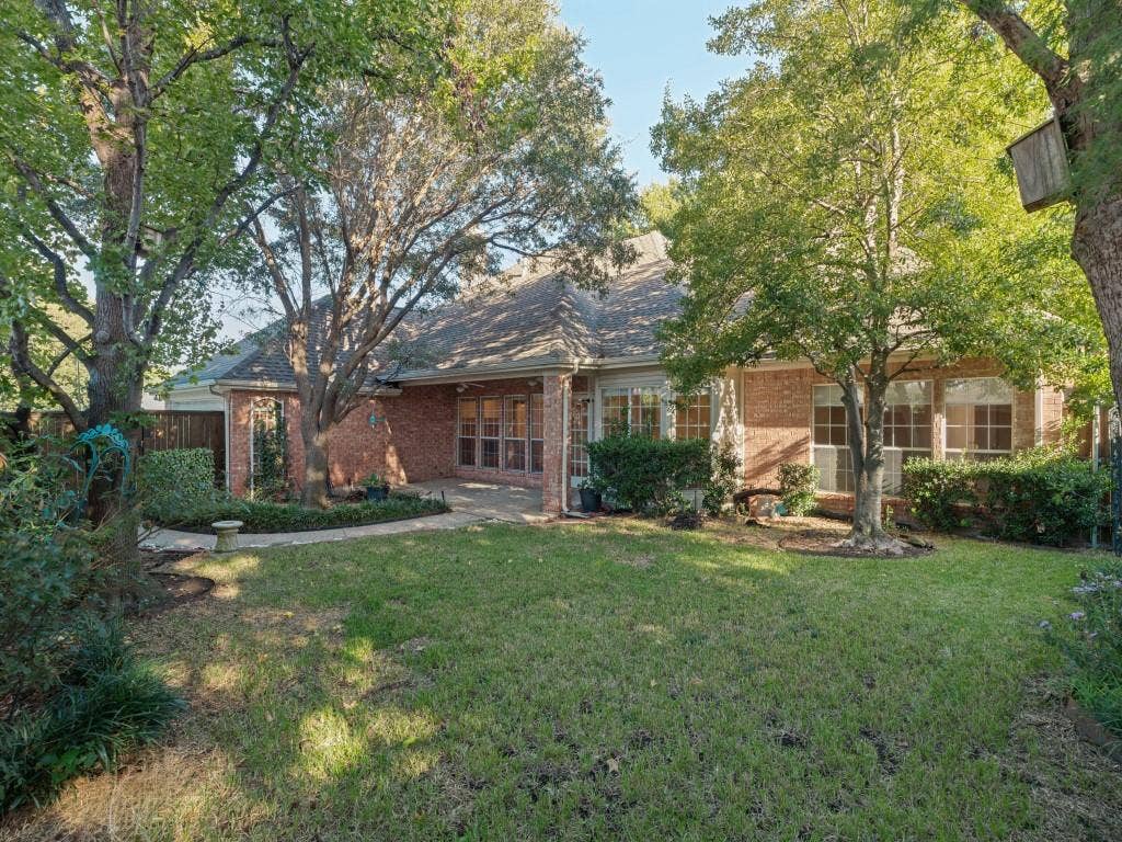 2817 Mayfair Lane, McKinney, TX 75071 Backyard featuring a brick exterior, stone-paved patio, expansive grass lawn, mature trees, and privacy fencing