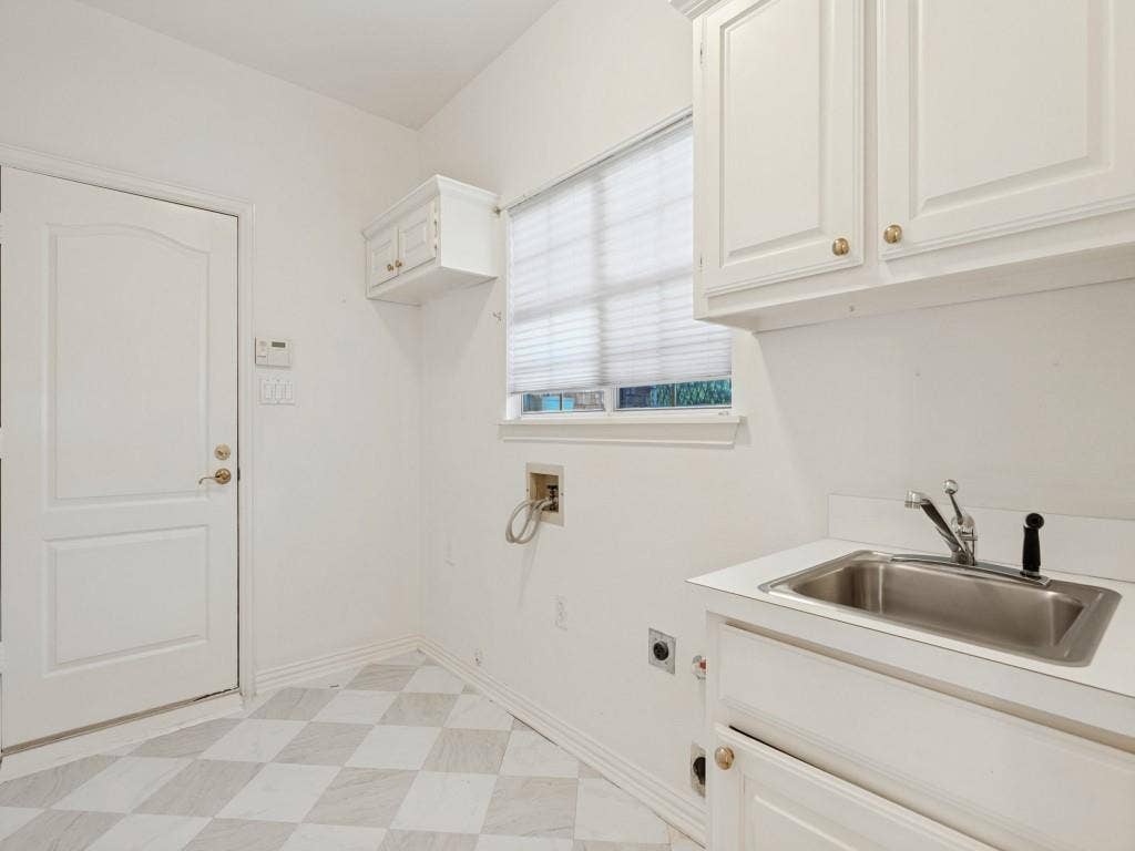 2817 Mayfair Lane, McKinney, TX 75071 Utility area featuring white built-in cabinetry, a stainless steel drop-in sink with a metal faucet, geometric tile flooring, and a solid-core door