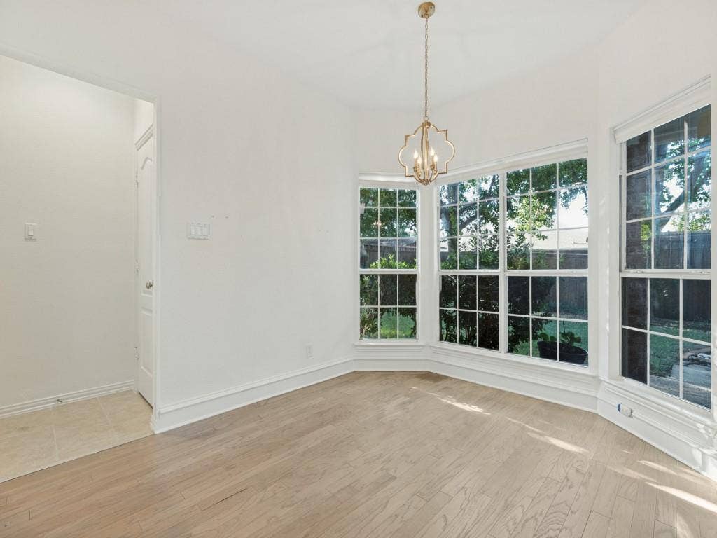 2817 Mayfair Lane, McKinney, TX 75071 Bay window featuring grid-pattern panes, wood-finish flooring, and a decorative gold-tone pendant light fixture