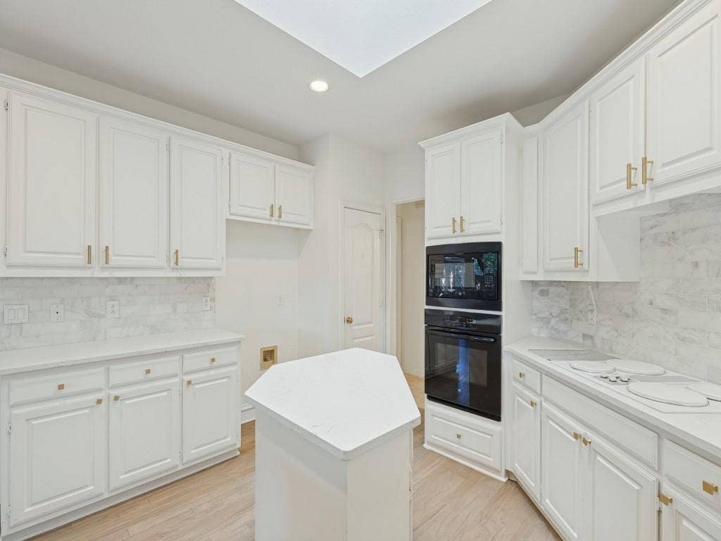 2817 Mayfair Lane, McKinney, TX 75071 Kitchen featuring white shaker-style cabinetry, a central island with a solid surface countertop, stone-finish backsplash, recessed lighting, and built-in double wall ovens