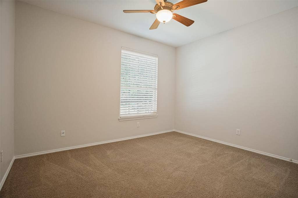 Additional bedroom with ceiling fan and neutral finishes