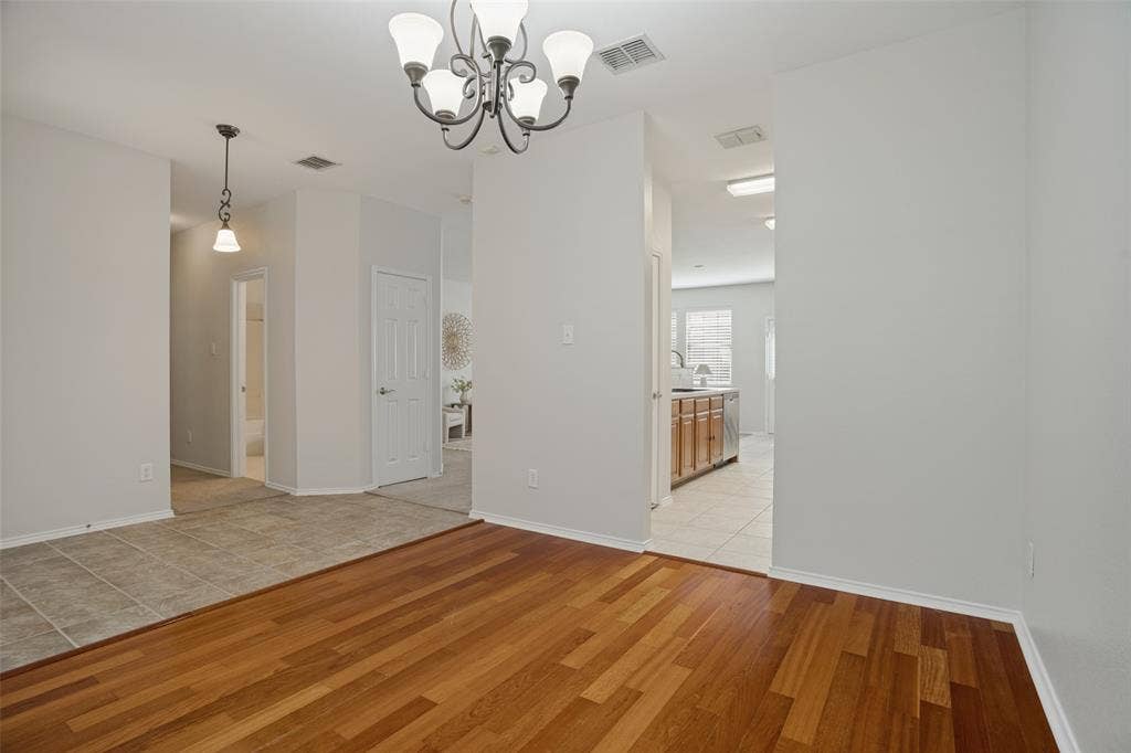 Flexible dining space with wood flooring and chandelier