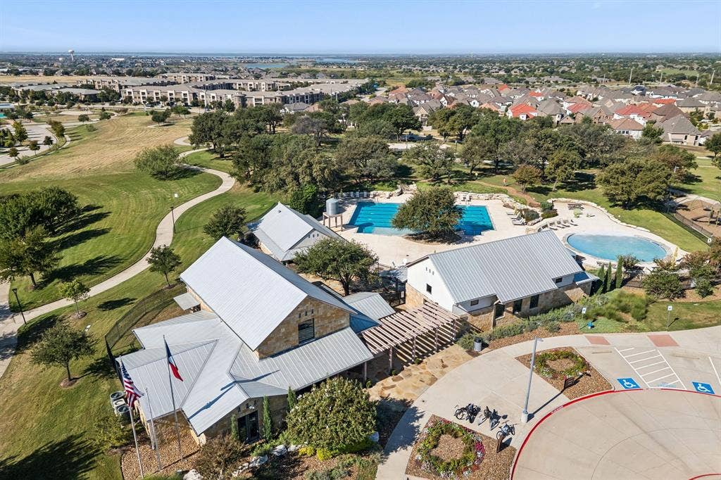 6448 Fire Creek Trail, Frisco, TX 75036 Community amenity complex featuring stone-exterior structures, metal roofing, dual outdoor swimming pools, and a wooden pergola