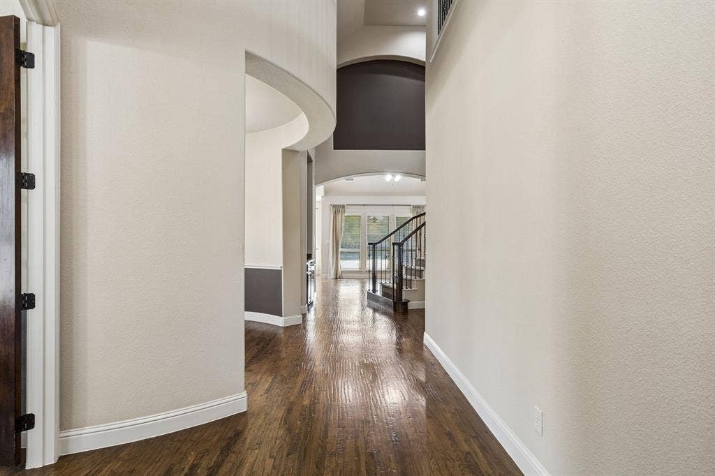 6448 Fire Creek Trail, Frisco, TX 75036 Foyer featuring wood-finish flooring, soaring ceilings with architectural archways, and a staircase with metal balusters