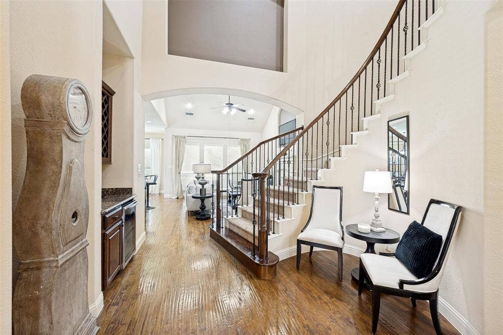 6448 Fire Creek Trail, Frisco, TX 75036 Grand foyer featuring soaring vaulted ceilings, wood-finish flooring, a built-in wet bar with dark cabinetry, and an ornate staircase with metal balusters