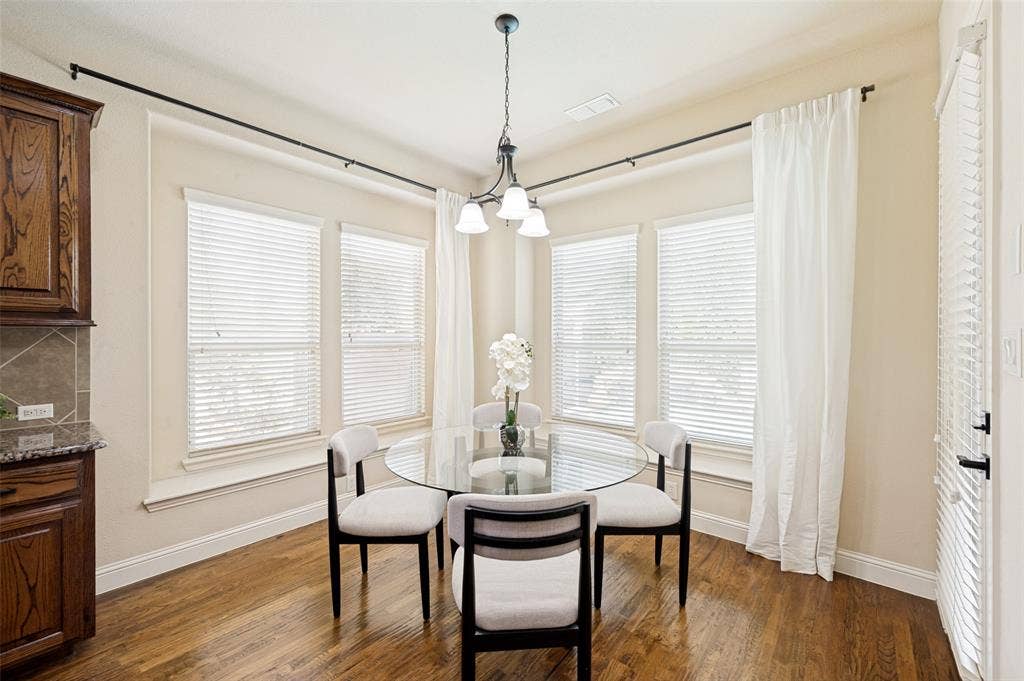 6448 Fire Creek Trail, Frisco, TX 75036 Corner area featuring wood-finish flooring, four multi-pane windows with horizontal blinds, and a three-light pendant fixture