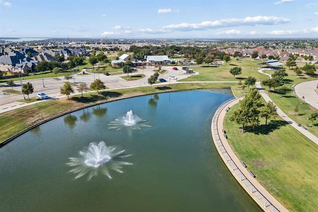 6448 Fire Creek Trail, Frisco, TX 75036 Pond featuring dual aerating fountains, concrete paved perimeter walkway, surrounding manicured green space, and mature trees