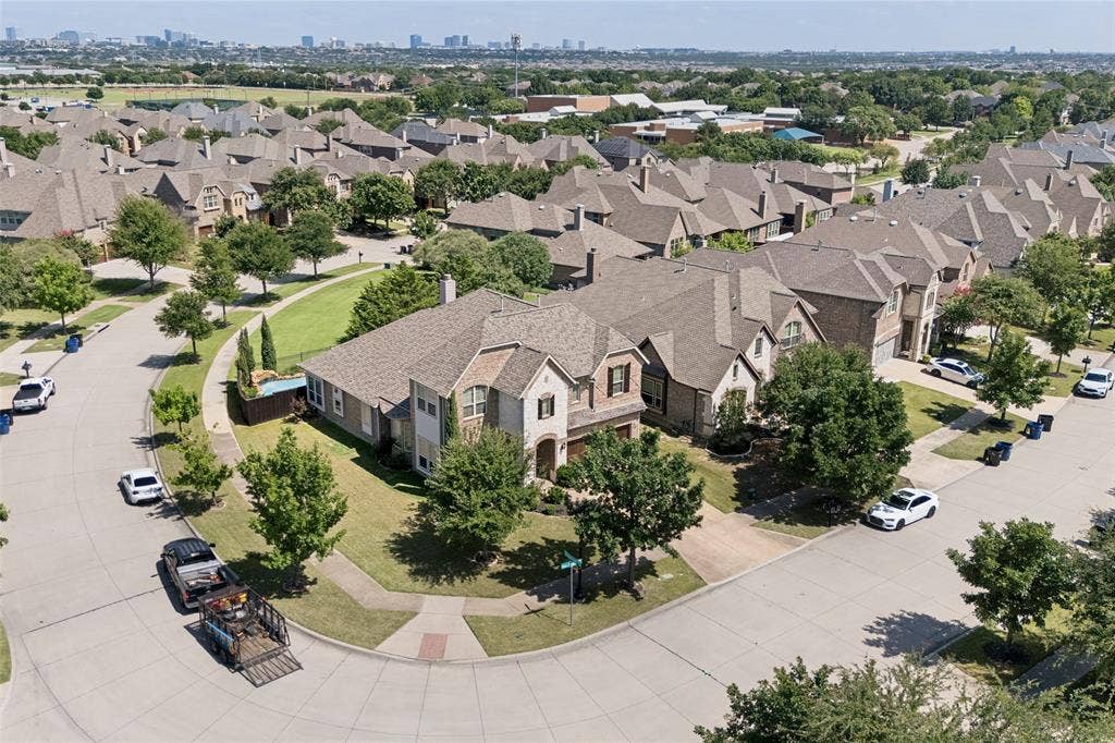 6448 Fire Creek Trail, Frisco, TX 75036 Corner lot residence featuring a multi-gabled roofline, stone and brick exterior, attached multi-car garage, and established landscaping