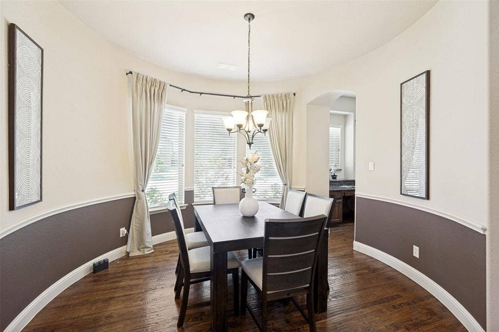 6448 Fire Creek Trail, Frisco, TX 75036 Curved wall design featuring two-tone paint, chair rail molding, wood-finish flooring, and a multi-light chandelier