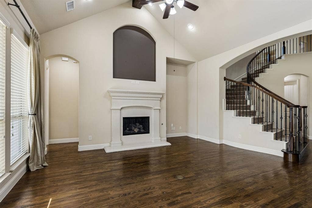 6448 Fire Creek Trail, Frisco, TX 75036 Vaulted ceiling, wood-finish flooring, central fireplace with a classic mantel, and a curved staircase featuring wrought-iron balusters
