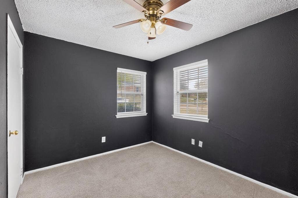 9651 Cherry Street, Frisco, TX 75033 Room featuring high-contrast charcoal walls, neutral carpeting, a central ceiling fan with integrated lighting, and dual windows with built-in blinds