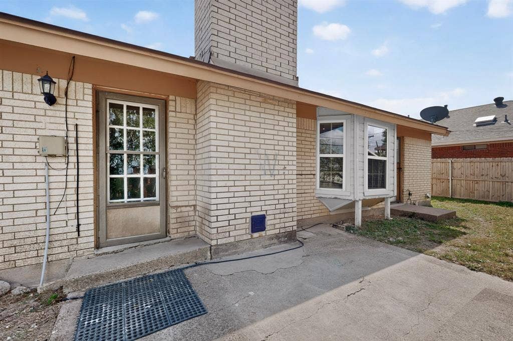 9651 Cherry Street, Frisco, TX 75033 Brick exterior featuring a masonry chimney, bay window, concrete patio, and grid-pattern glass entry door