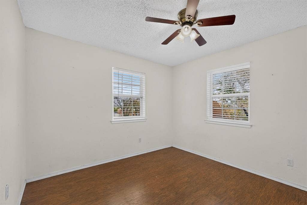 9651 Cherry Street, Frisco, TX 75033 Room featuring wood-finish flooring, two windows with horizontal blinds, and a ceiling fan with integrated light fixture