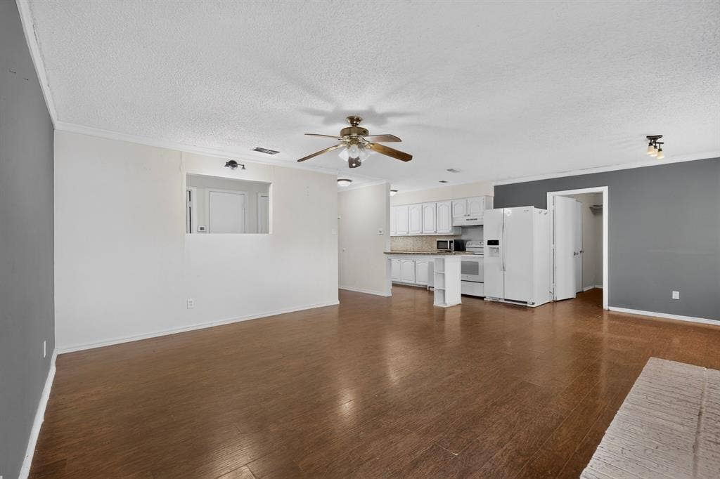 9651 Cherry Street, Frisco, TX 75033 Open-concept interior featuring wood-finish flooring, a kitchen breakfast bar, white cabinetry, and a ceiling fan with integrated lighting