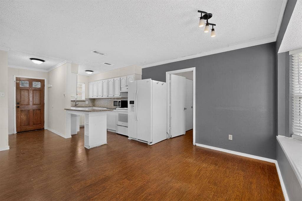 9651 Cherry Street, Frisco, TX 75033 Kitchen area featuring white cabinetry, a peninsula with stone-finish countertop, wood-finish flooring, and a solid wood front entry door