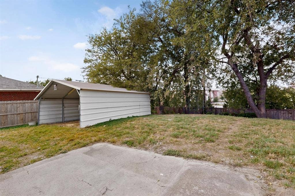 9651 Cherry Street, Frisco, TX 75033 Backyard featuring a metal-panel carport, concrete patio, grass lawn, and wood privacy fencing