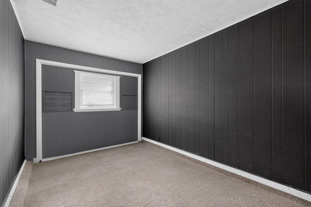 9651 Cherry Street, Frisco, TX 75033 Room featuring dark-toned vertical paneled walls, neutral carpeting, and a single-pane window with trim detail