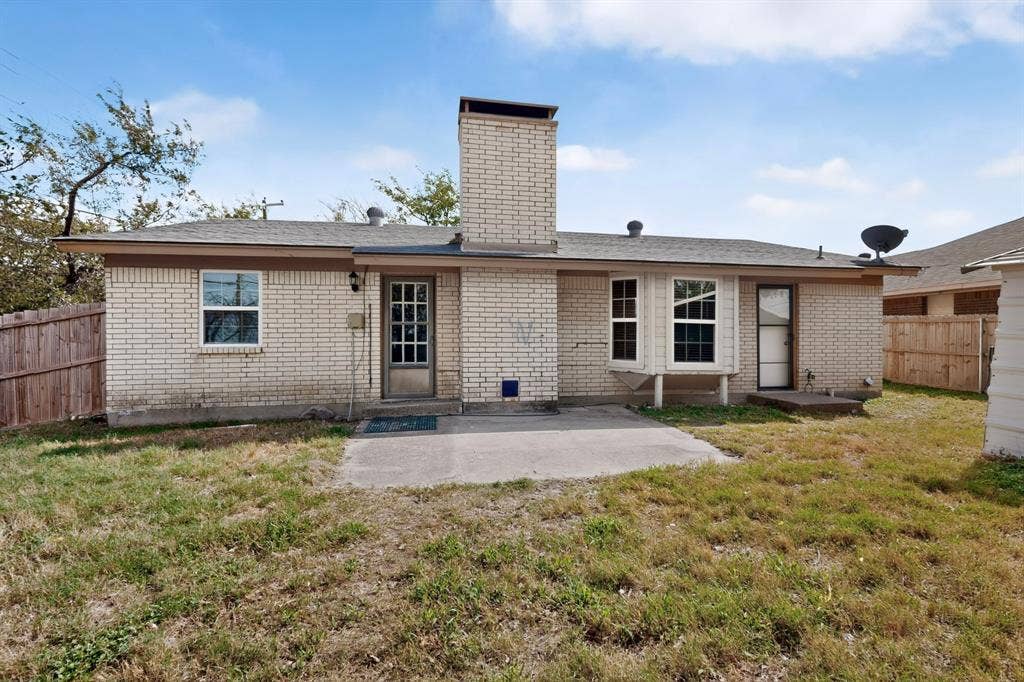 9651 Cherry Street, Frisco, TX 75033 Rear exterior featuring a brick facade, central masonry chimney, concrete patio, and a bay window