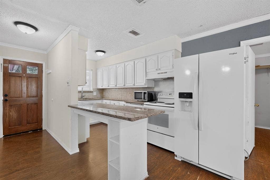 9651 Cherry Street, Frisco, TX 75033 Kitchen featuring white cabinetry, stone-finish countertops, a raised breakfast bar, wood-finish flooring, and white appliances