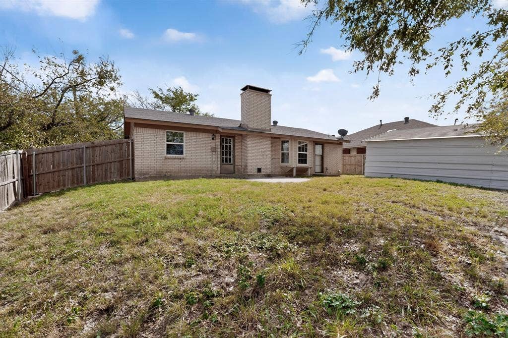 9651 Cherry Street, Frisco, TX 75033 Brick exterior residence featuring a central masonry chimney, rear patio, wooden privacy fencing, and a detached structure