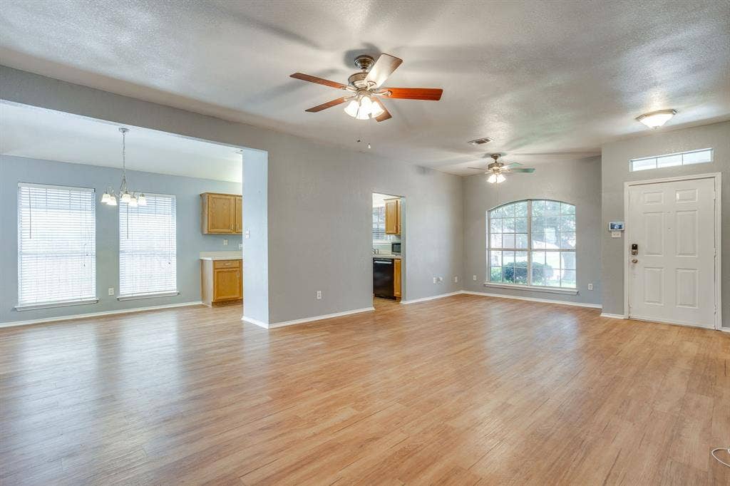 6221 St Leonard Drive, Arlington, TX 76001 Open-concept interior featuring wood-finish flooring, dual ceiling fans, arched window, and overhead pendant lighting