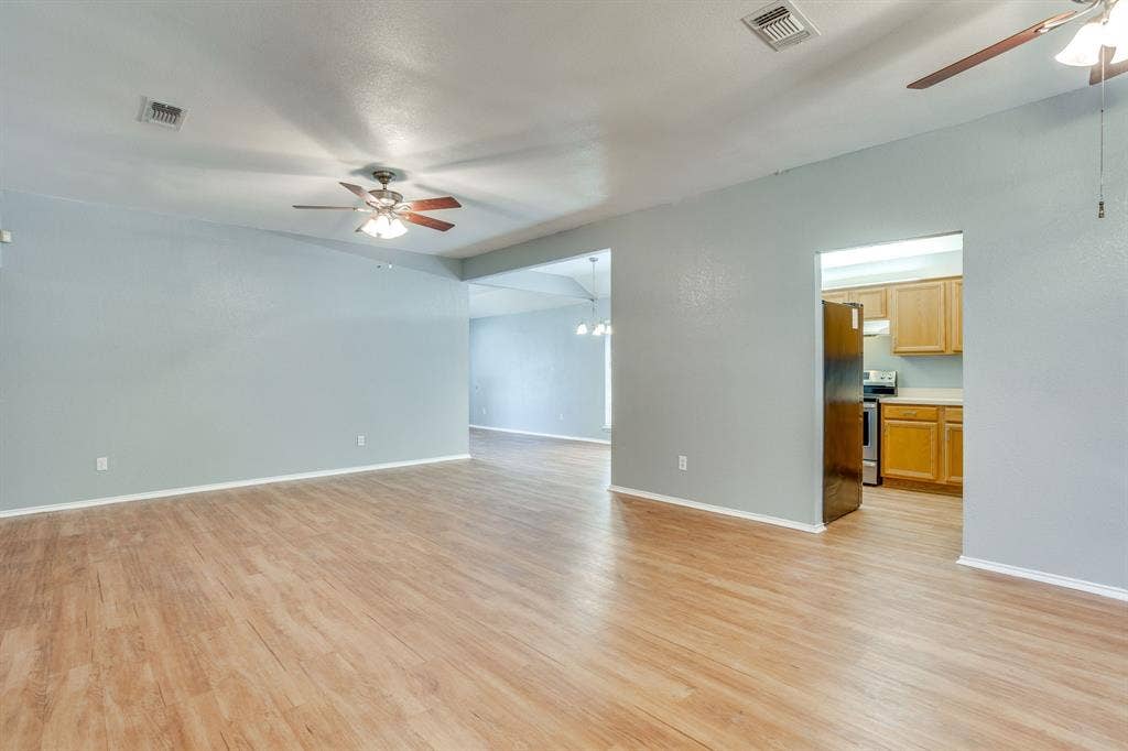 6221 St Leonard Drive, Arlington, TX 76001 Open-concept area featuring wood-finish flooring, vaulted ceilings, and dual ceiling fans