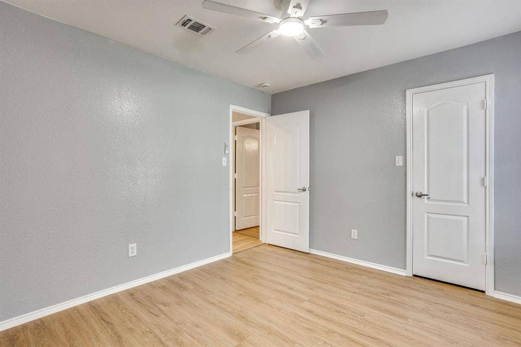 6221 St Leonard Drive, Arlington, TX 76001 Neutral-toned walls paired with light-finish wood-finish flooring, featuring a ceiling fan with integrated lighting and interior doors with two-panel architectural detailing