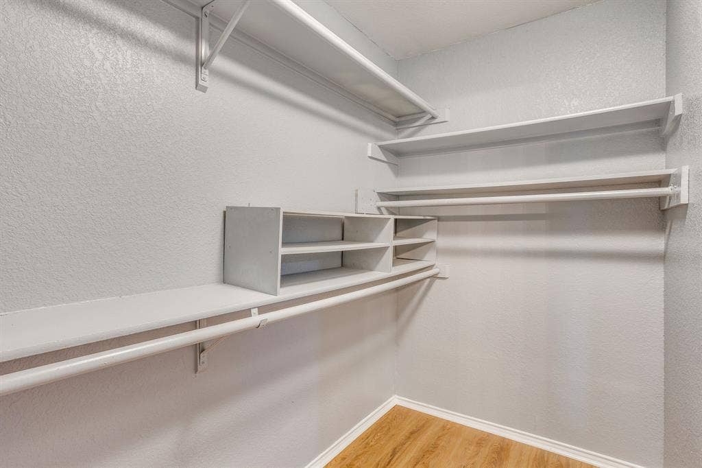 6221 St Leonard Drive, Arlington, TX 76001 Walk-in storage space featuring wood-finish flooring, white shelving tiers, and multiple built-in garment rods
