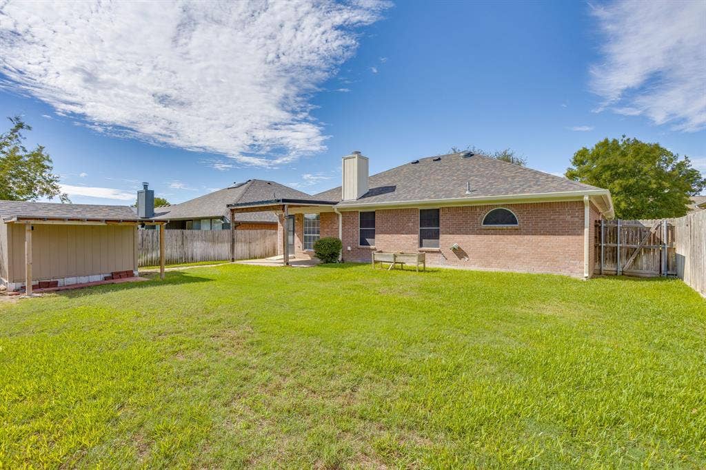 6221 St Leonard Drive, Arlington, TX 76001 Brick exterior residence featuring a covered patio, a detached storage structure, and a fenced backyard