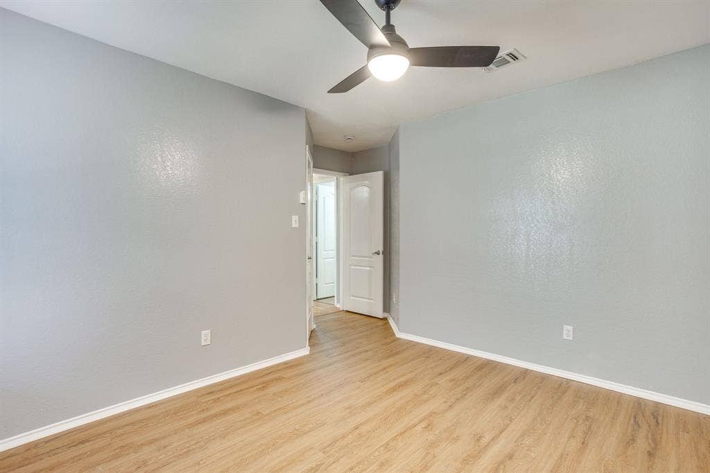 6221 St Leonard Drive, Arlington, TX 76001 Neutral-toned walls, wood-finish flooring, and a ceiling-mounted matte black light fixture with an integrated fan