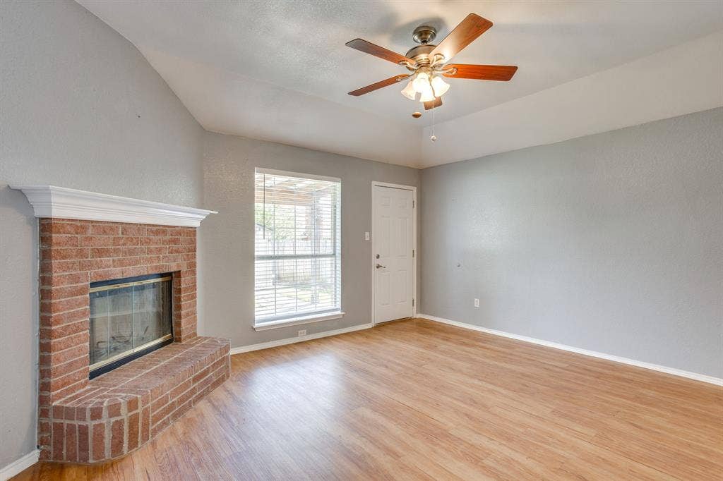 6221 St Leonard Drive, Arlington, TX 76001 Vaulted ceilings, red brick fireplace with a white mantel, wood-finish flooring, and a ceiling fan with integrated lighting