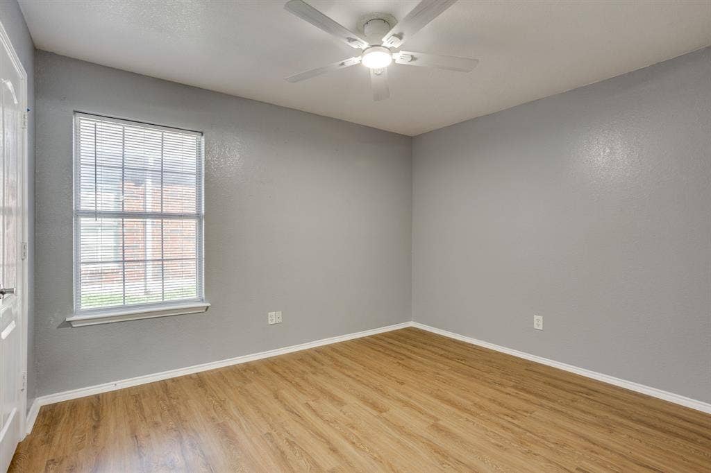 6221 St Leonard Drive, Arlington, TX 76001 Neutral-toned interior featuring wood-finish flooring, a ceiling fan with integrated lighting, and a window with horizontal blinds