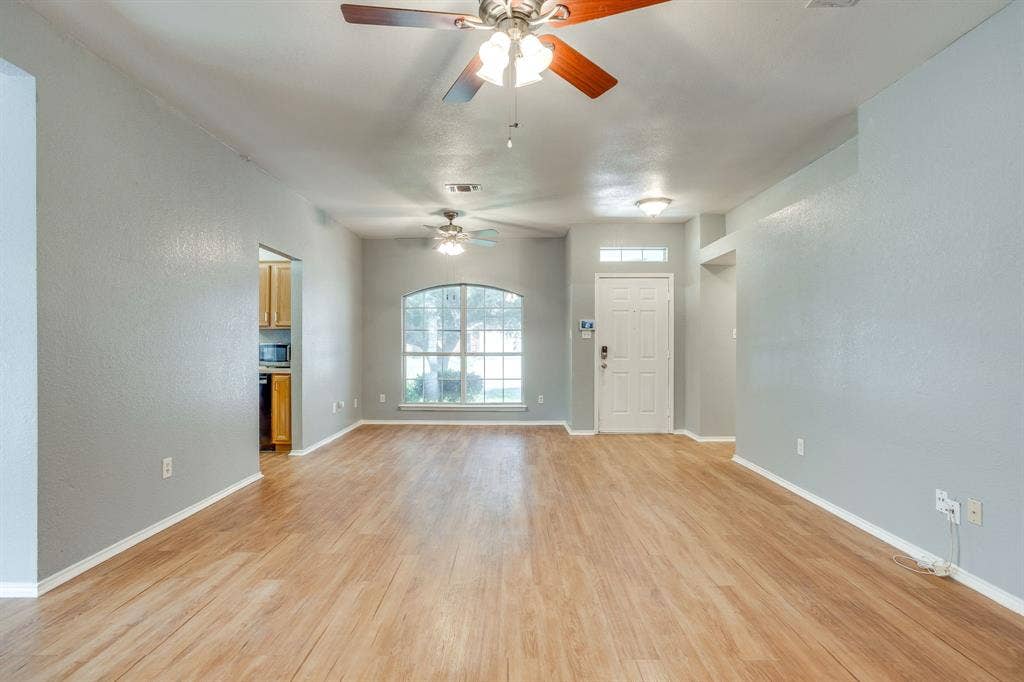 6221 St Leonard Drive, Arlington, TX 76001 Open interior featuring wood-finish flooring, two ceiling fans, and an arched window
