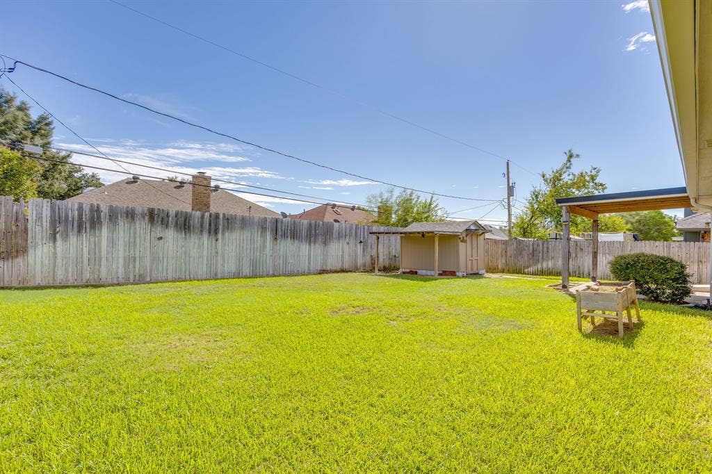 6221 St Leonard Drive, Arlington, TX 76001 Backyard featuring a grass lawn, perimeter wood fencing, a storage shed, and a covered patio area