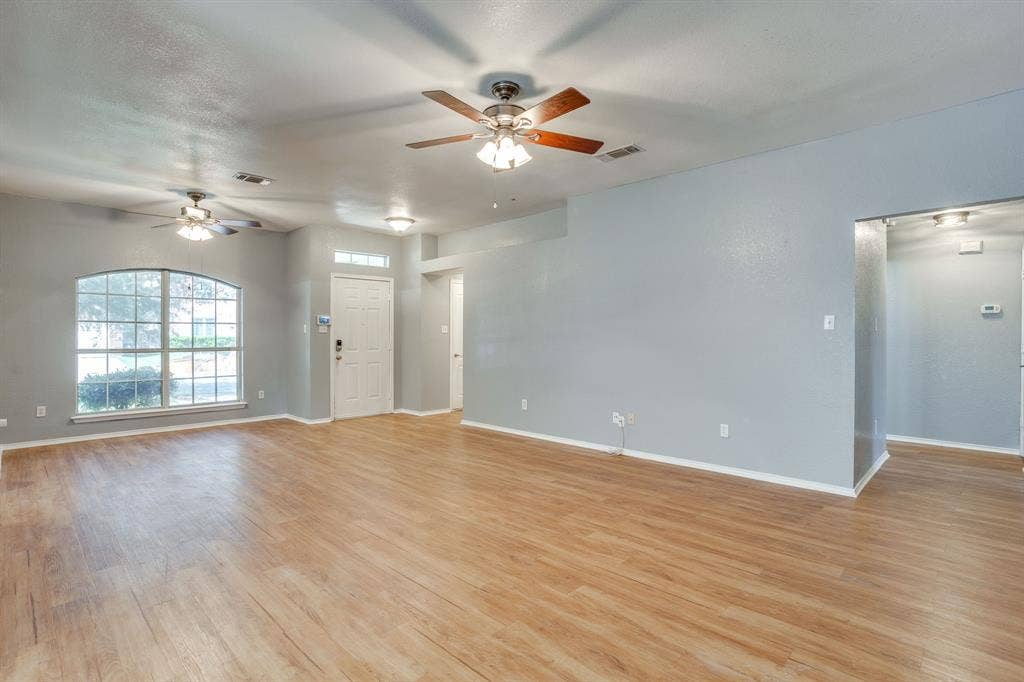 6221 St Leonard Drive, Arlington, TX 76001 Interior featuring wood-finish flooring, two ceiling fans with integrated lighting, a multi-pane arched window, and a paneled entry door with a transom window