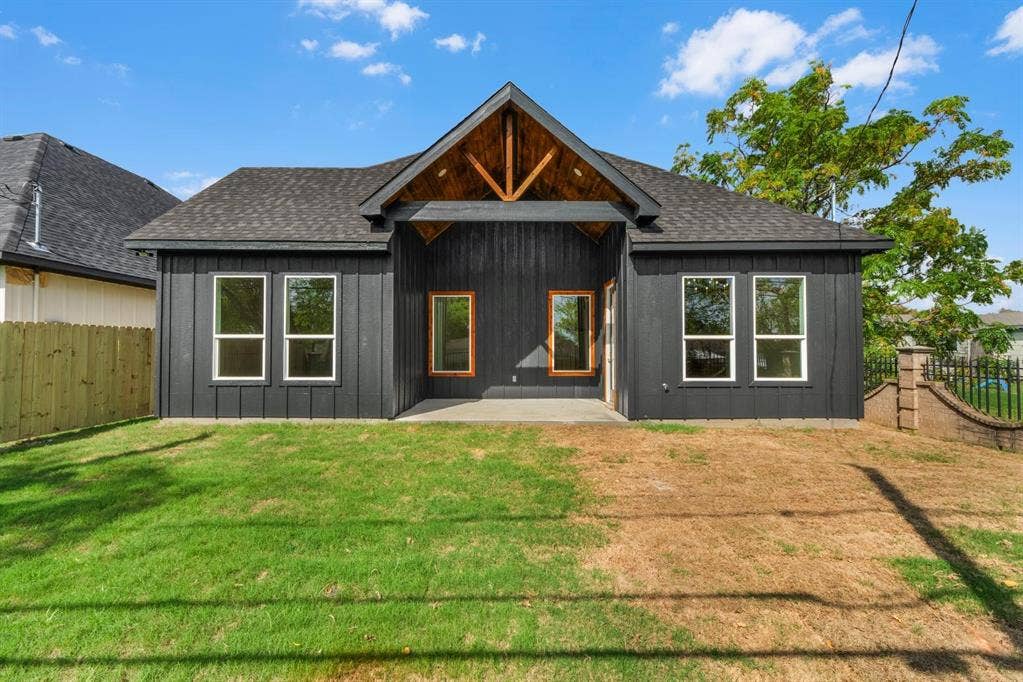 Exterior featuring vertical board-and-batten siding, a covered rear patio with wood-paneled gable ceiling, and a prominent timber truss beam