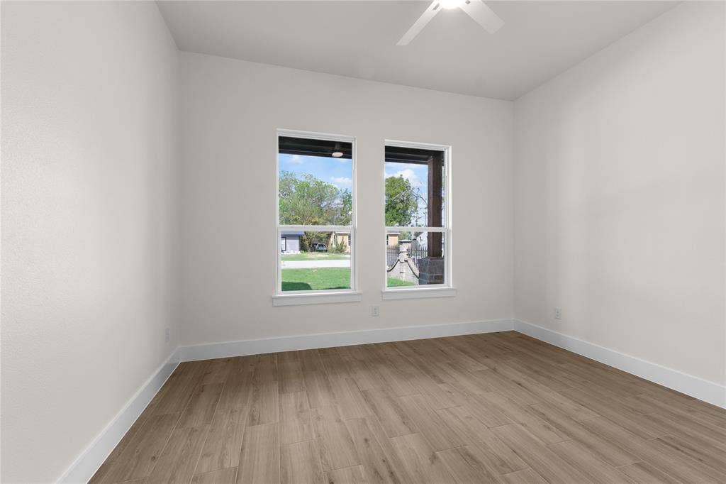 Neutral interior featuring wood-finish flooring, two dual-pane windows, and a ceiling-mounted light fixture