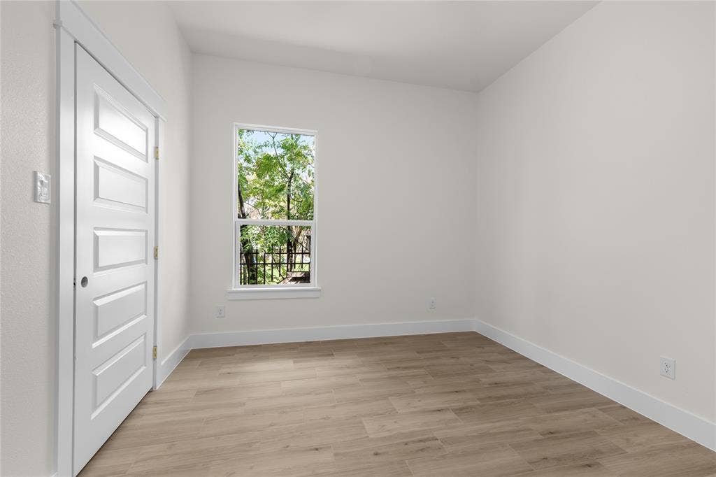 Neutral-toned interior space featuring wood-finish flooring, a single-hung window, and a white five-panel interior door